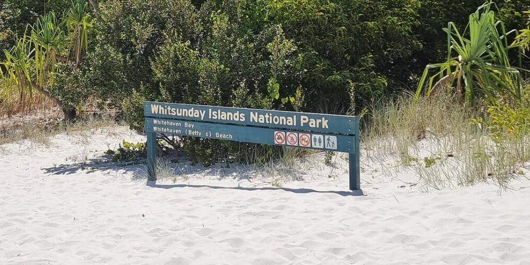 Official whitsunday islands national park sign on white sand reading "whitehaven bay" and "whitehaven (betty's) beach", marking the northern area as whitehaven bay rather than whitehaven beach